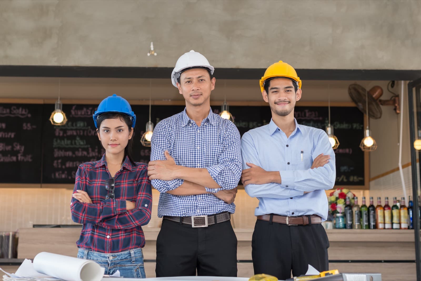 A crew of contractors in hard hats with blueprints at a restaurant build-out site.
