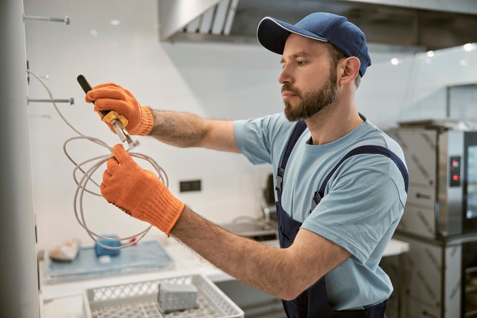 A maintenance technician servicing equipment in a commercial restaurant kitchen.