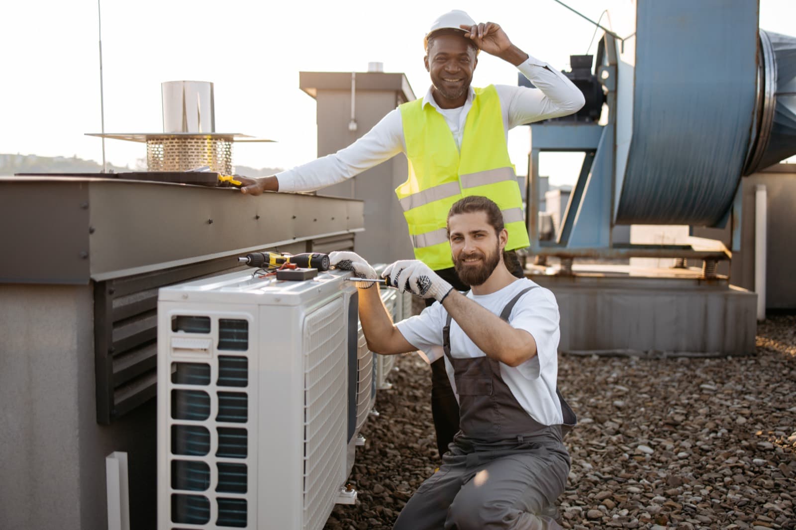 HVAC technicians installing a new air-conditioning system on a commercial job site.